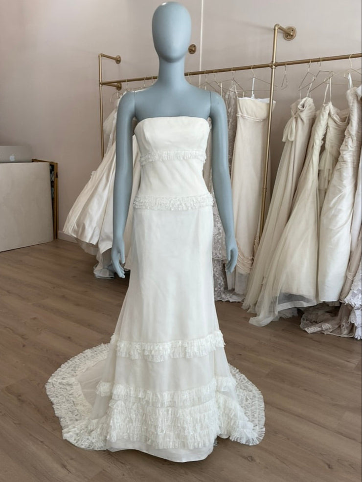 White strapless gown on a mannequin in a bridal shop setting.